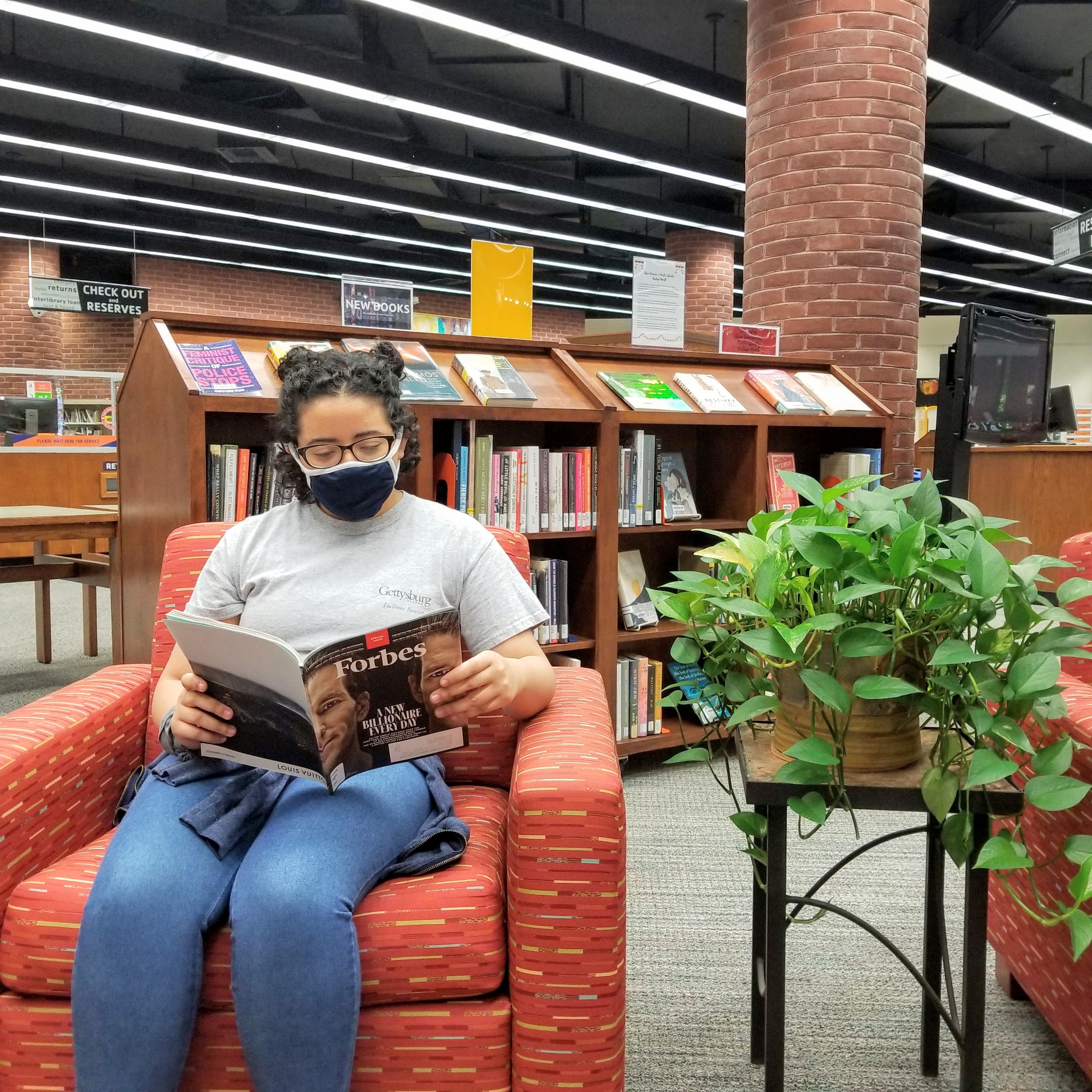 Image of woman reading a magazine in an armchair.