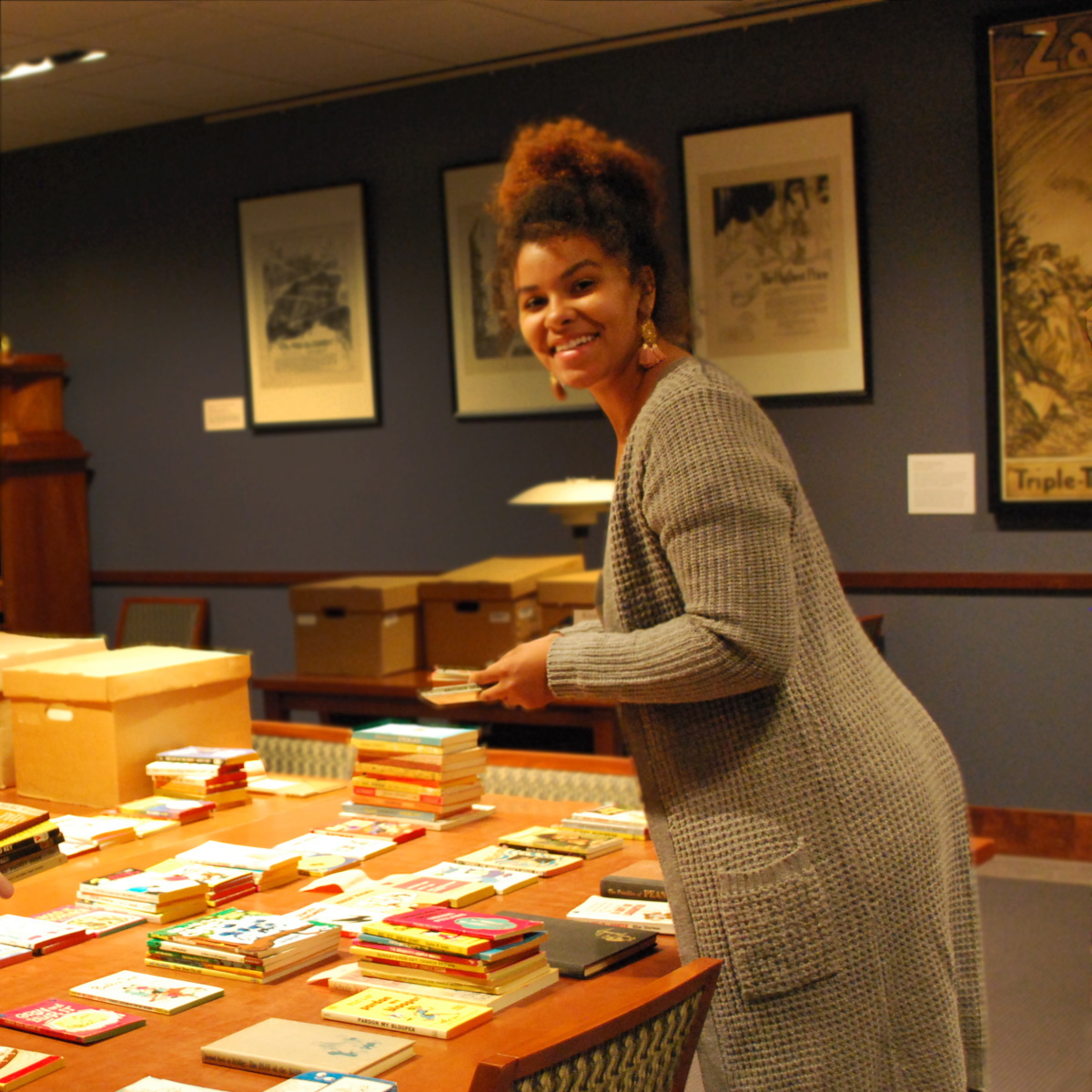 Image of an intern posing with papers and materials on a table in Special Collections.