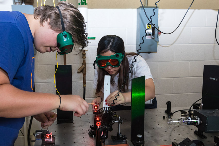 Students viewing the Picket's Charge Plasma Device in a lab with a professor