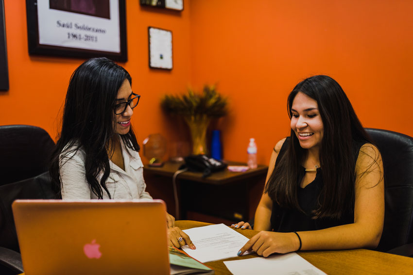 Business majors talking in front of a computer