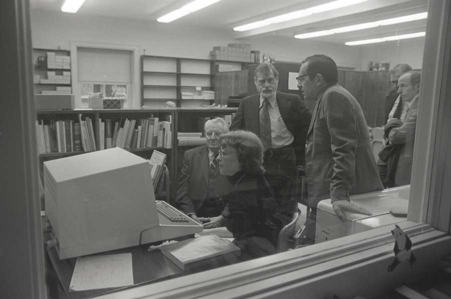 Four people crowded around a computer in an office setting