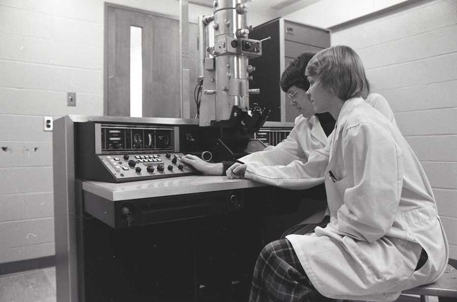 Two scientists in front of a microscope