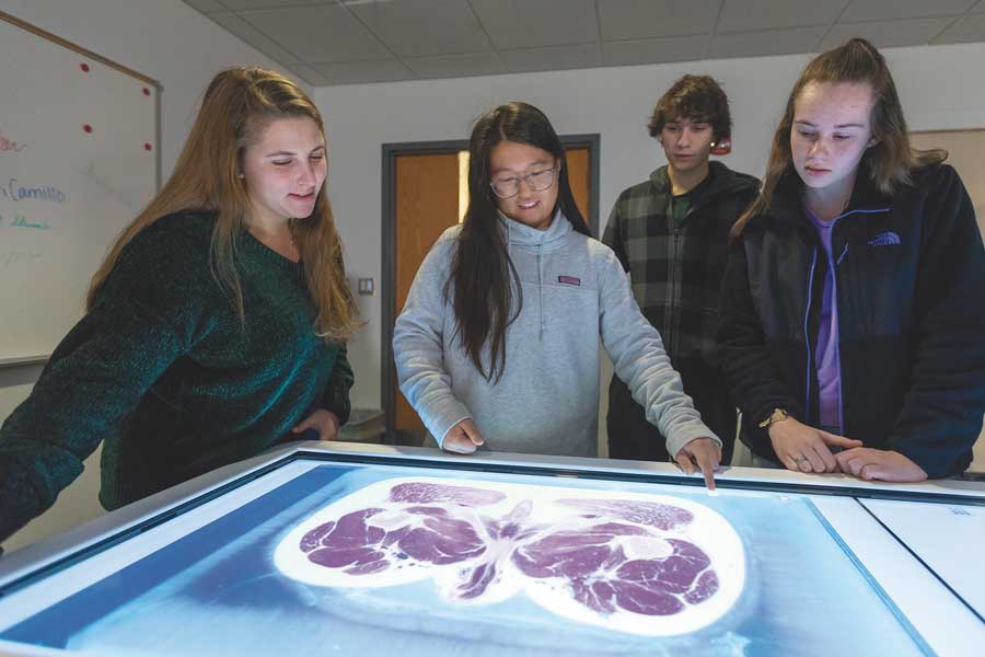 Students gathered around a table with a touchscreen computer interface