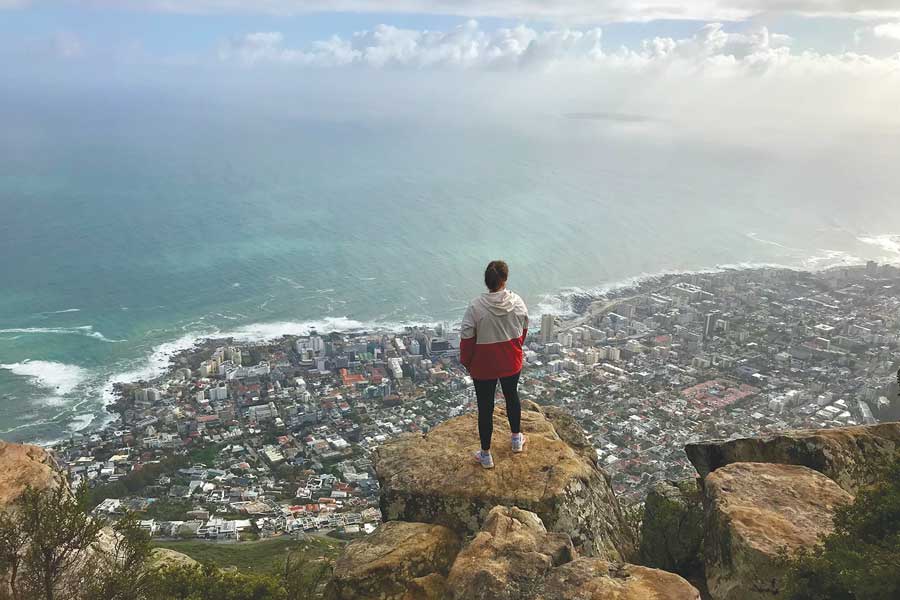 Brynn Griffith standing on a cliff side in front of a city coast line