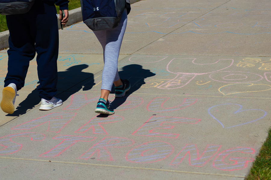 Students walking on sidewalks with chalk drawings on them