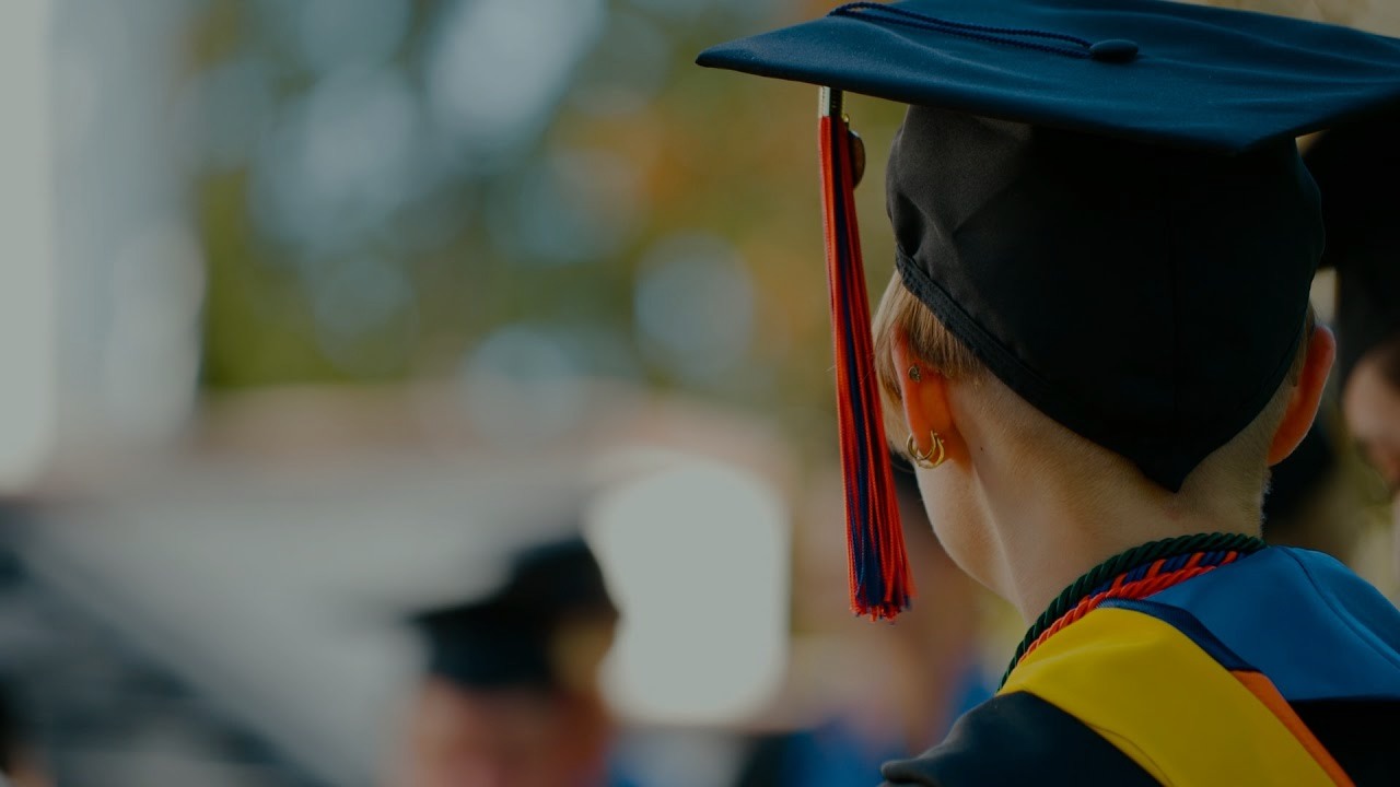 Woman wearing a commencement cap and gown from behind