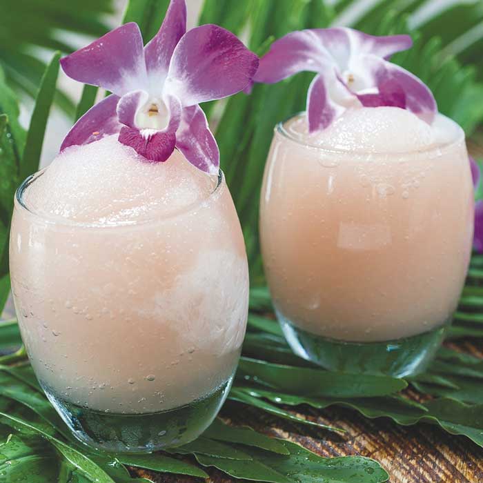 Two small frozen drinks with flowers on top of them