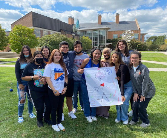 Gettysburg College students standing in front of the Science Center with a paper sign