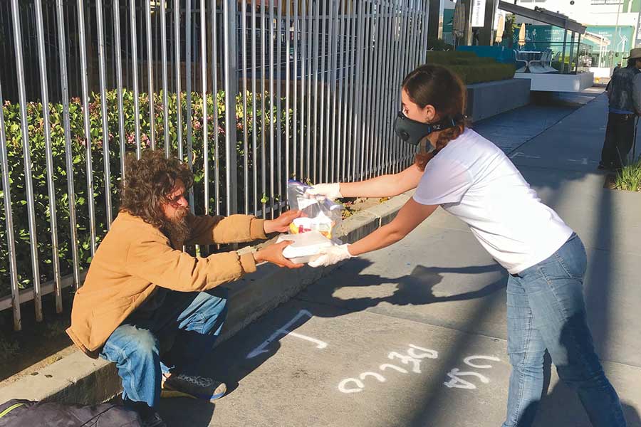 Woman handing a homeless man a bag of food