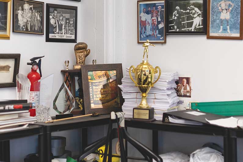 A shelf with trophies and framed photos on the wall above it