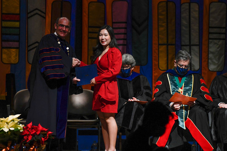 A graduate shaking Bob Iuliano's hand on stage