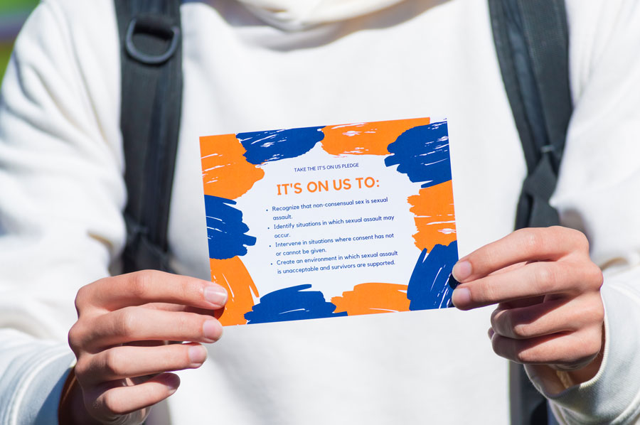 Student holding the Its On Us pledge card