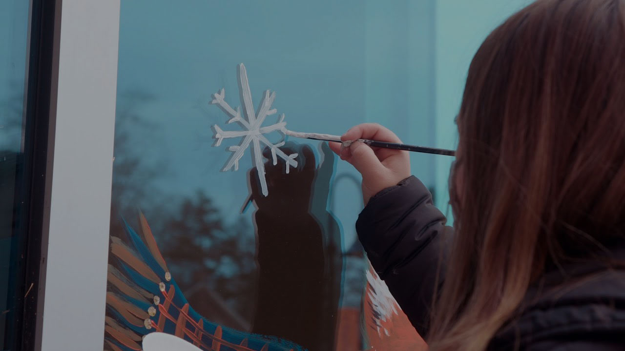 Woman painting a snowflake on glass