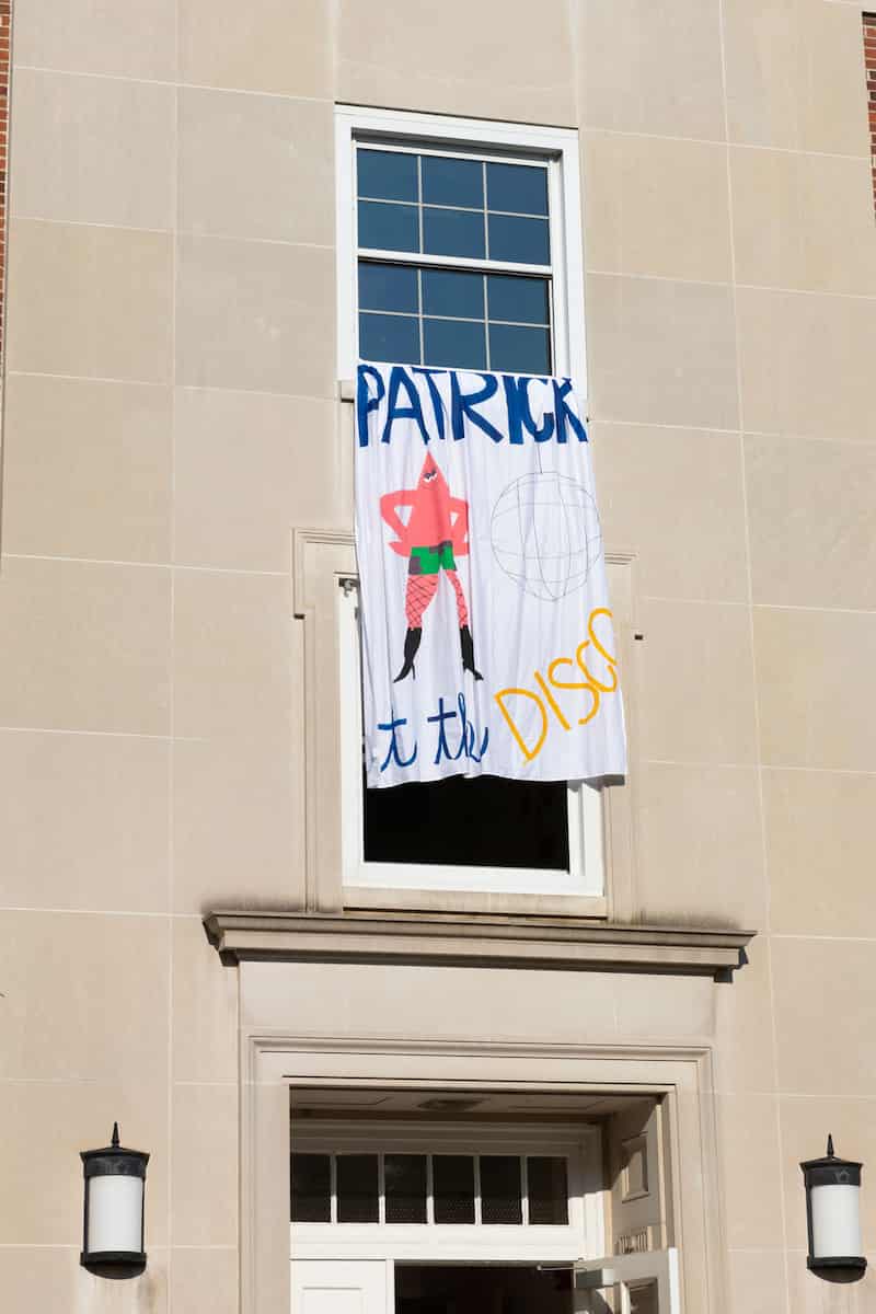 Patrick at the Disco banner with fishnets, heels, and disco ball hangs from dorm room window