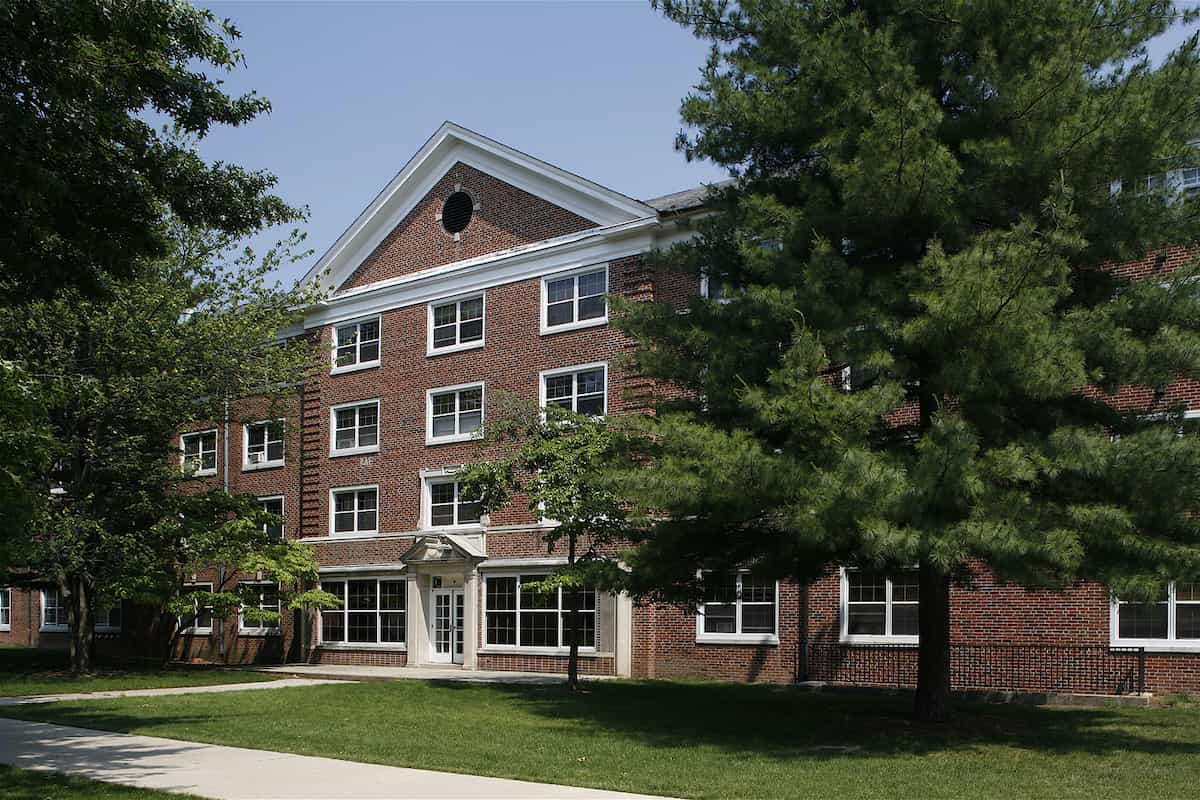 red brick dorm building, large pine tree, and blue sky