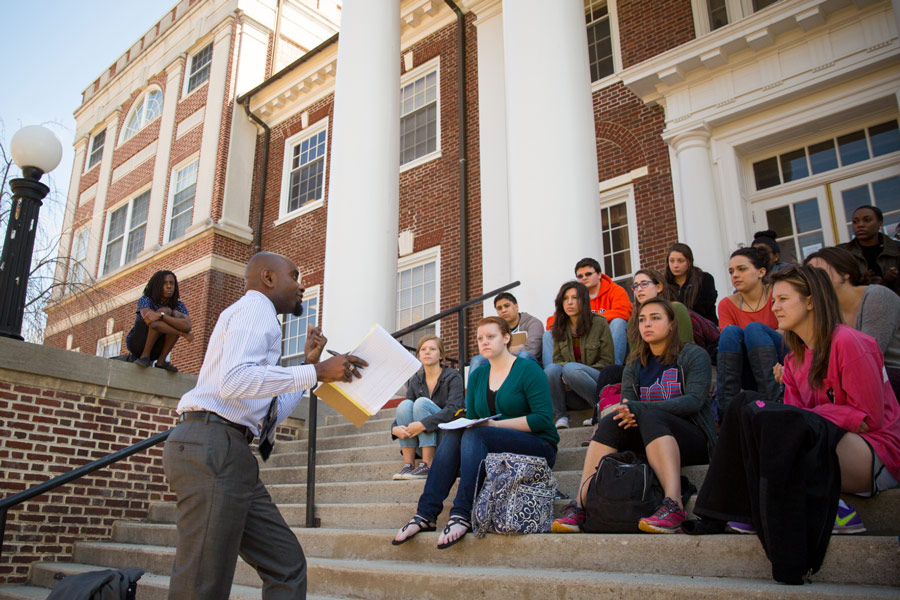 Prof. Hakim Mohandas Amani Williams teaching a class outside on the stairs of Breidenbaugh Hall