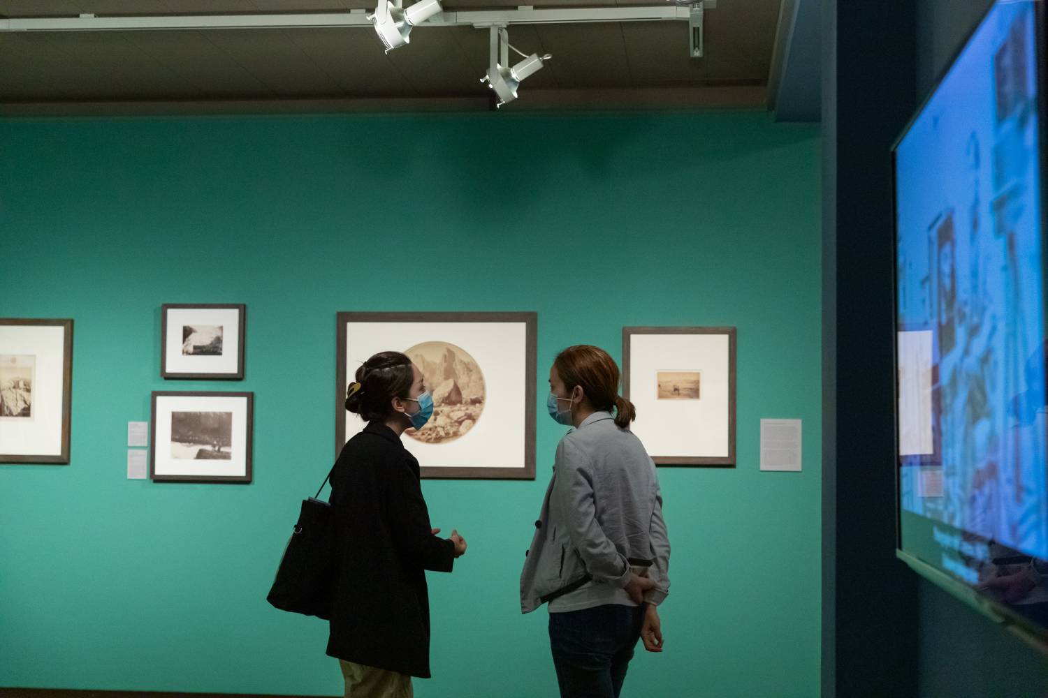 Two attendees talking to one another in front of a piece of art