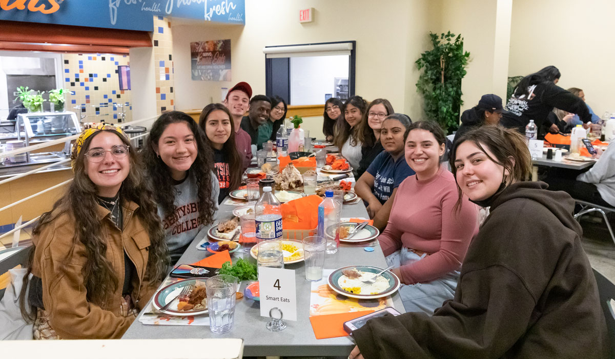 Students sitting at a long table together with food on the table