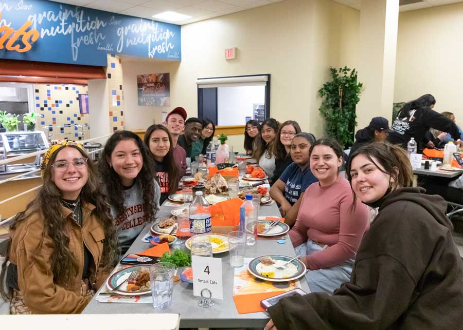 Students sitting at a table covered in thanksgiving food