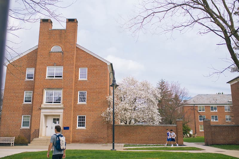 Stine Hall’s red brick against green spring grass and pale pink blossoms of the trees