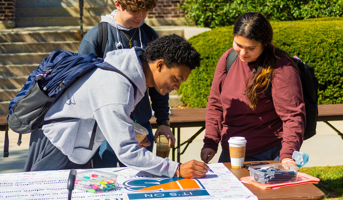 Student signing Its On Us poster