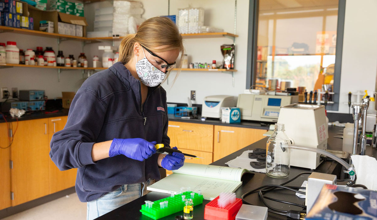 Student wearing a mask and doing research in a lab