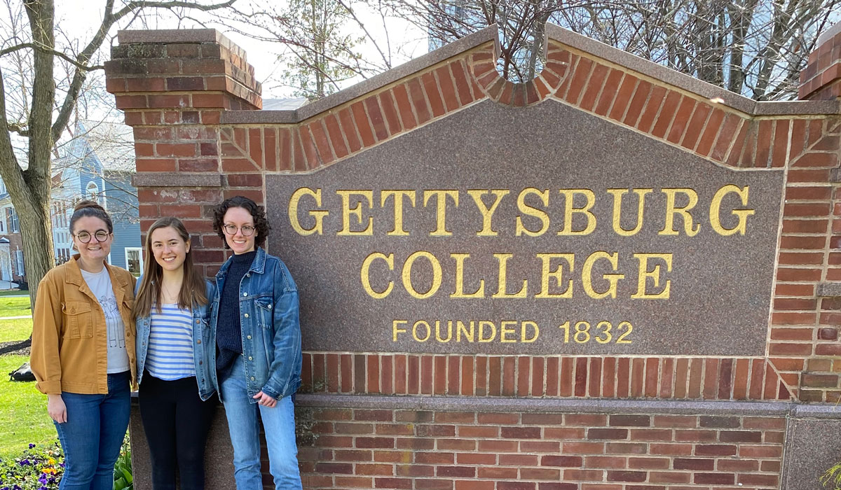 Friends stand in front of the Gettysburg College sign