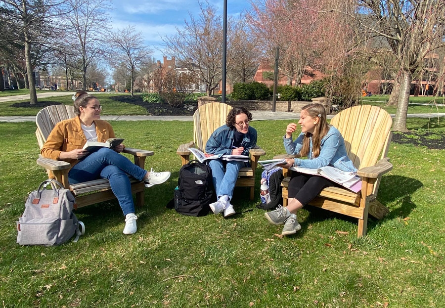 Friends study outside on Adirondack chairs