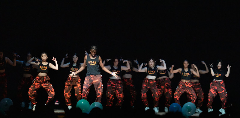 Students wearing orange camouflage pants dancing on stage