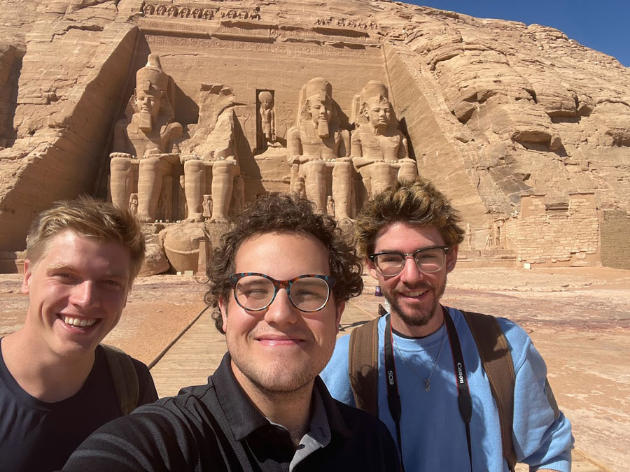Brandon with friends in front of a row of stone statues of Egyptian Kings