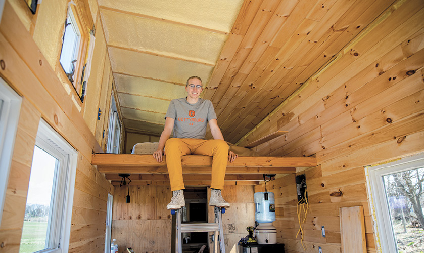 Zachary De Besche ’22 sitting on the upper floor of his tiny home