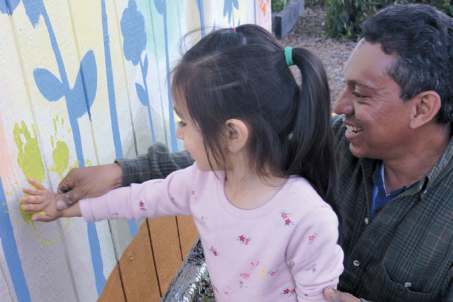 Child using their hand to place a handprint on a mural