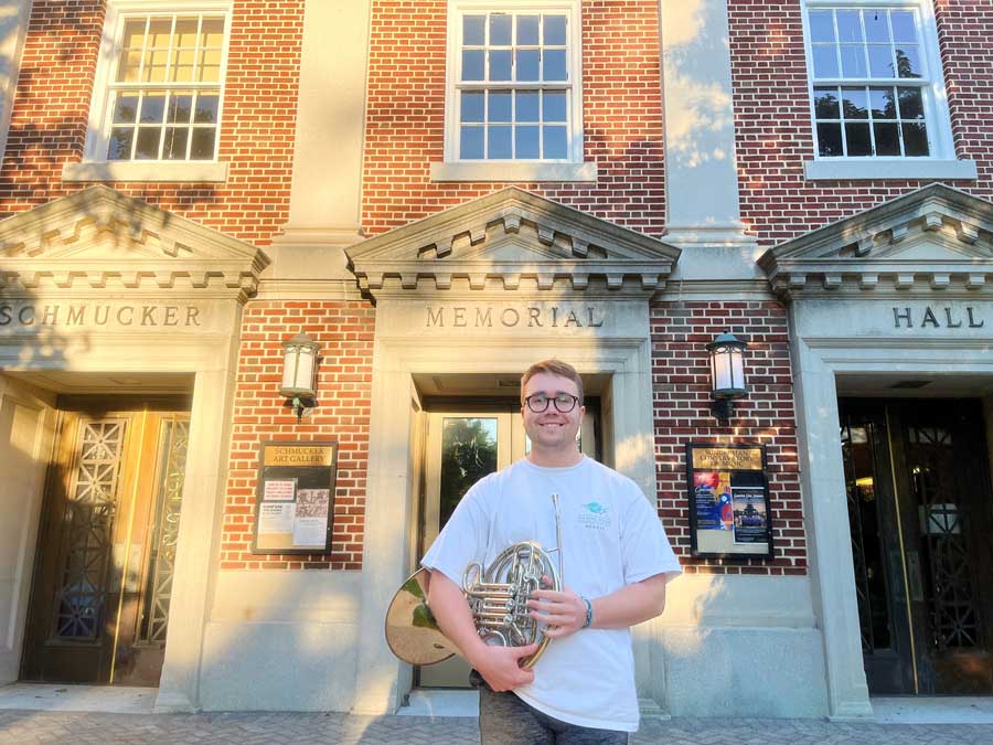 Ronnie Moyer standing outside Schmucker Hall with his french horn