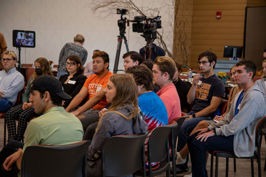 Students sitting and watching a presentation at a town hall