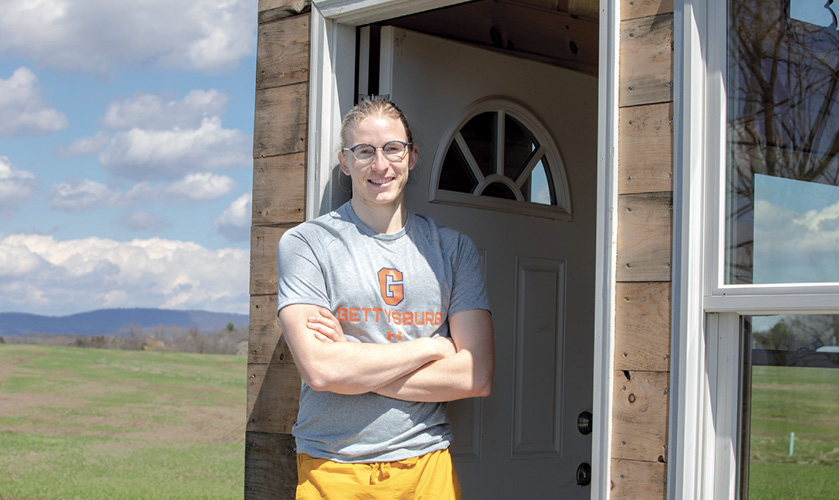 Zachary De Besche ’22 in the doorway of his tiny home