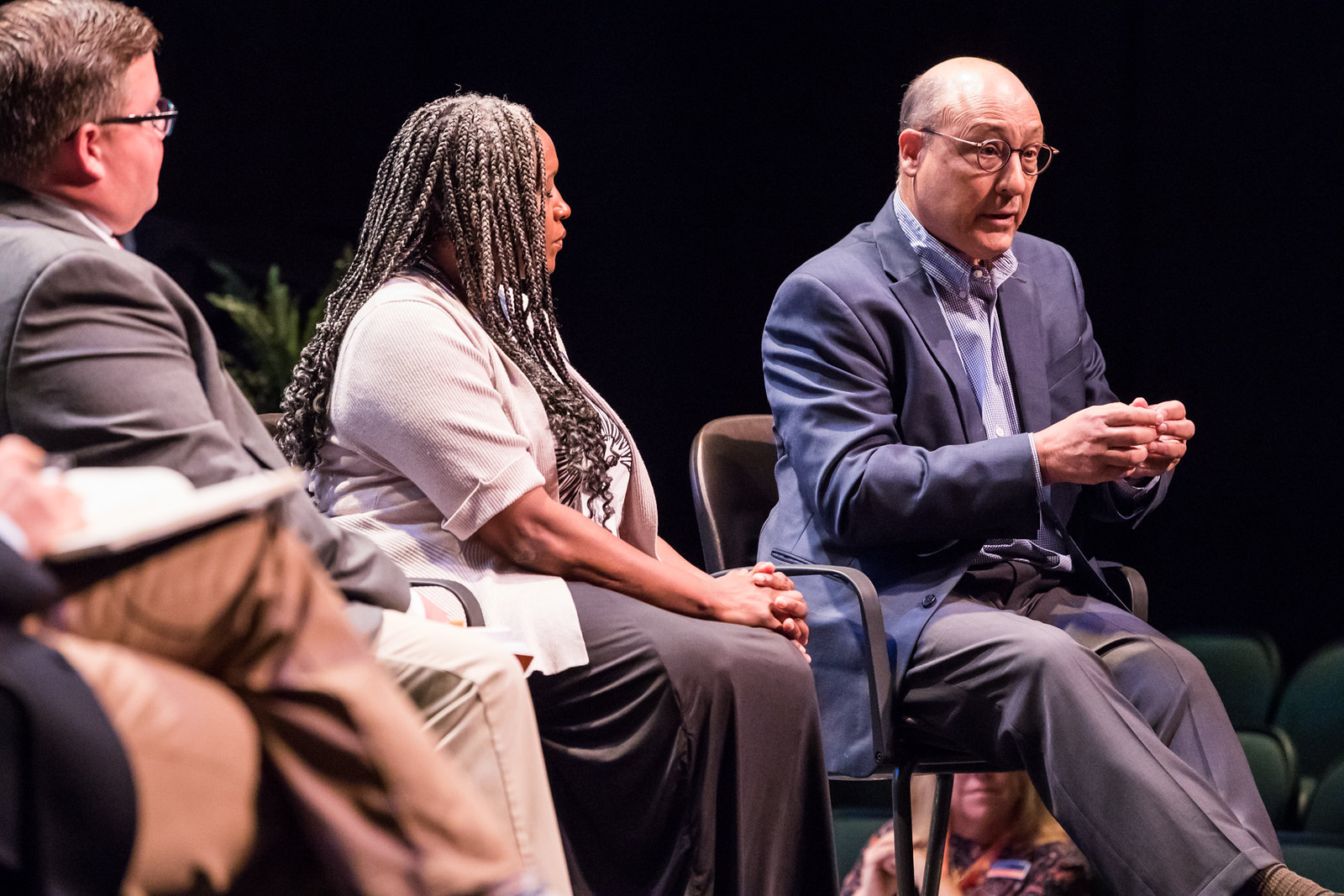 Three individuals in a panel discussion on stage