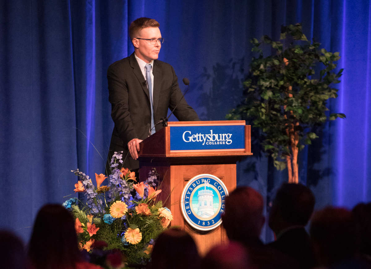 Young alum presents at podium during dinner