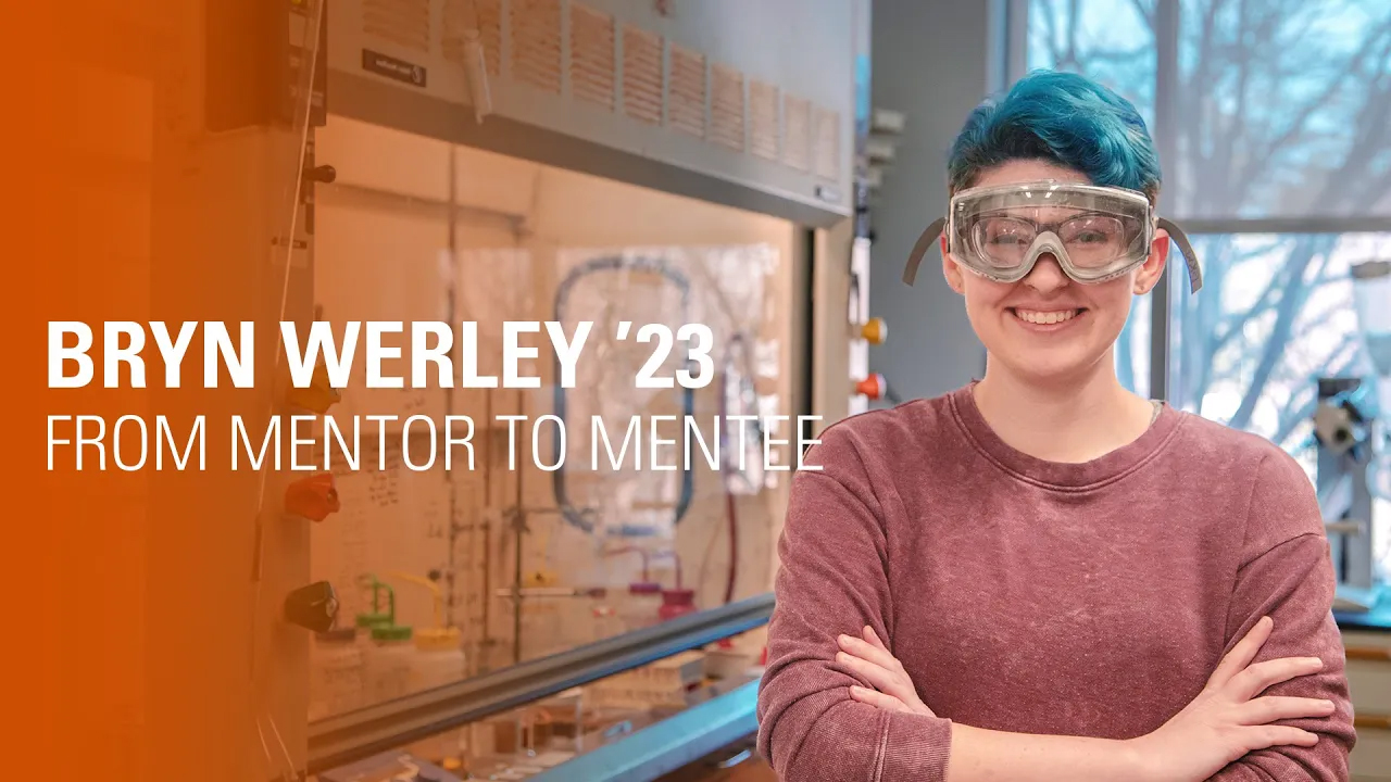 Young college student wearing science goggles smiles at camera