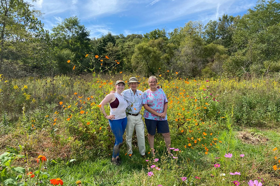 Verbrugge, Radin, and Biology Prof. Betty Ferster standing a garden