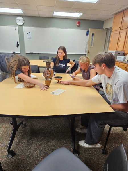 Students examining Ancient Greek vases in class.