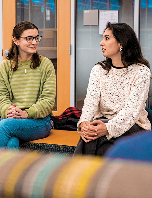 Alisha LeVine ’25 (right) talks with peers in the College Union Building.