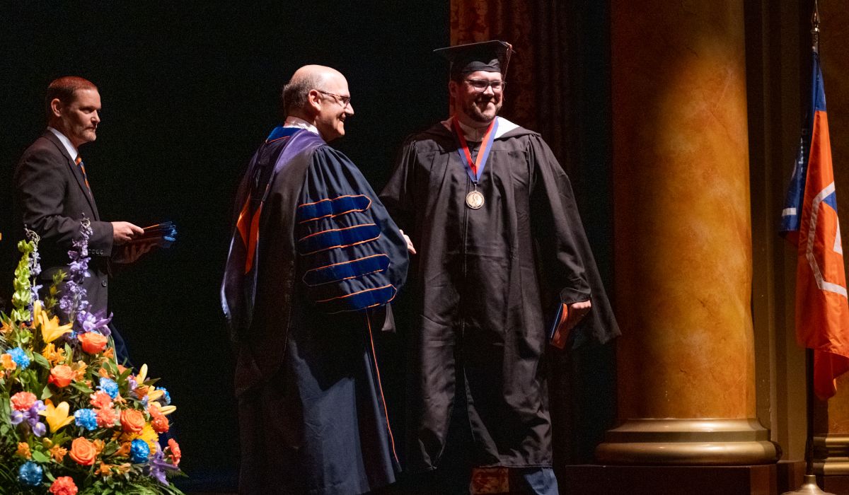 A graduate shaking the hand of President Bob