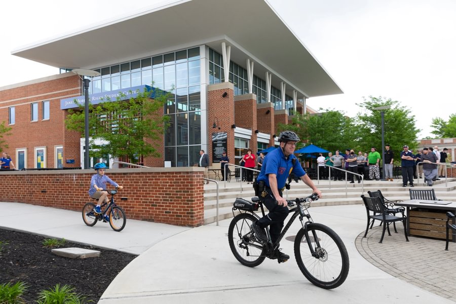 Campus Safety officer biking outside College Union Building.