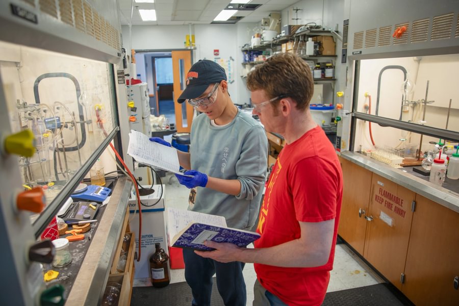 A student and professor reviewing notes together in a science lab