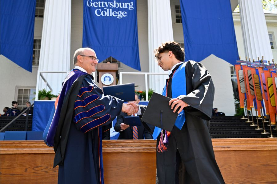 President Bob Iuliano greeting graduates at commencement.