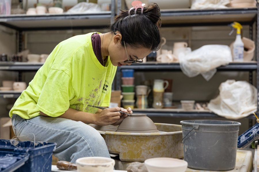 Student shaping clay with their hands during a ceramics class.