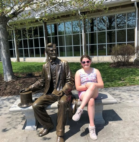 Kara Woods ’29 as a fifth grader sitting next to the Abraham Lincoln statue outside the Gettysburg National Military Park Museum and Visitor Center.