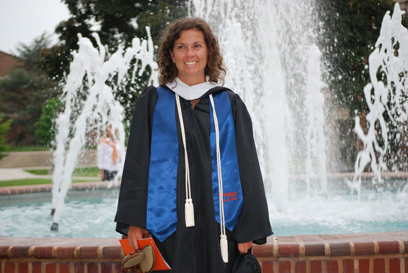 Katie Lobosco '09 in graduation robes in front of a water fountain