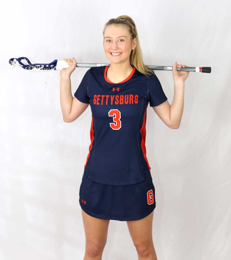 Liza Barr posing in her lacrosse uniform with her lacrosse stick