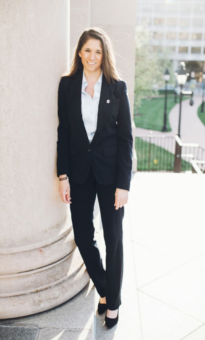 Amada Bond standing near a column in dress attire